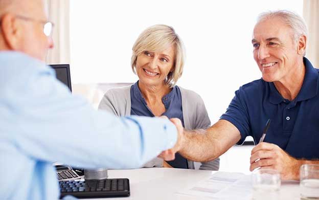 senior couple sitting across from their elder law attorney, shaking hands