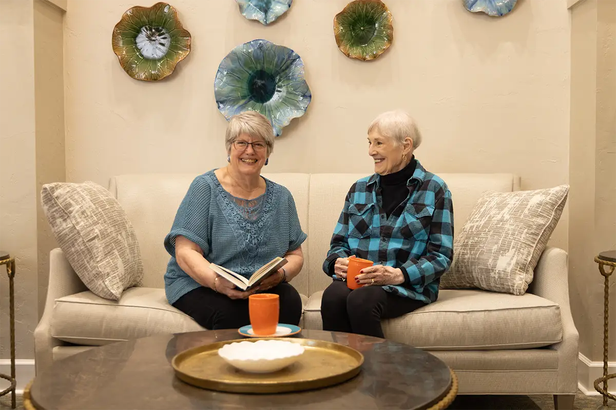 Small round glass dining table with two cushioned chairs, elegantly set for a meal in a cozy independent living residence.