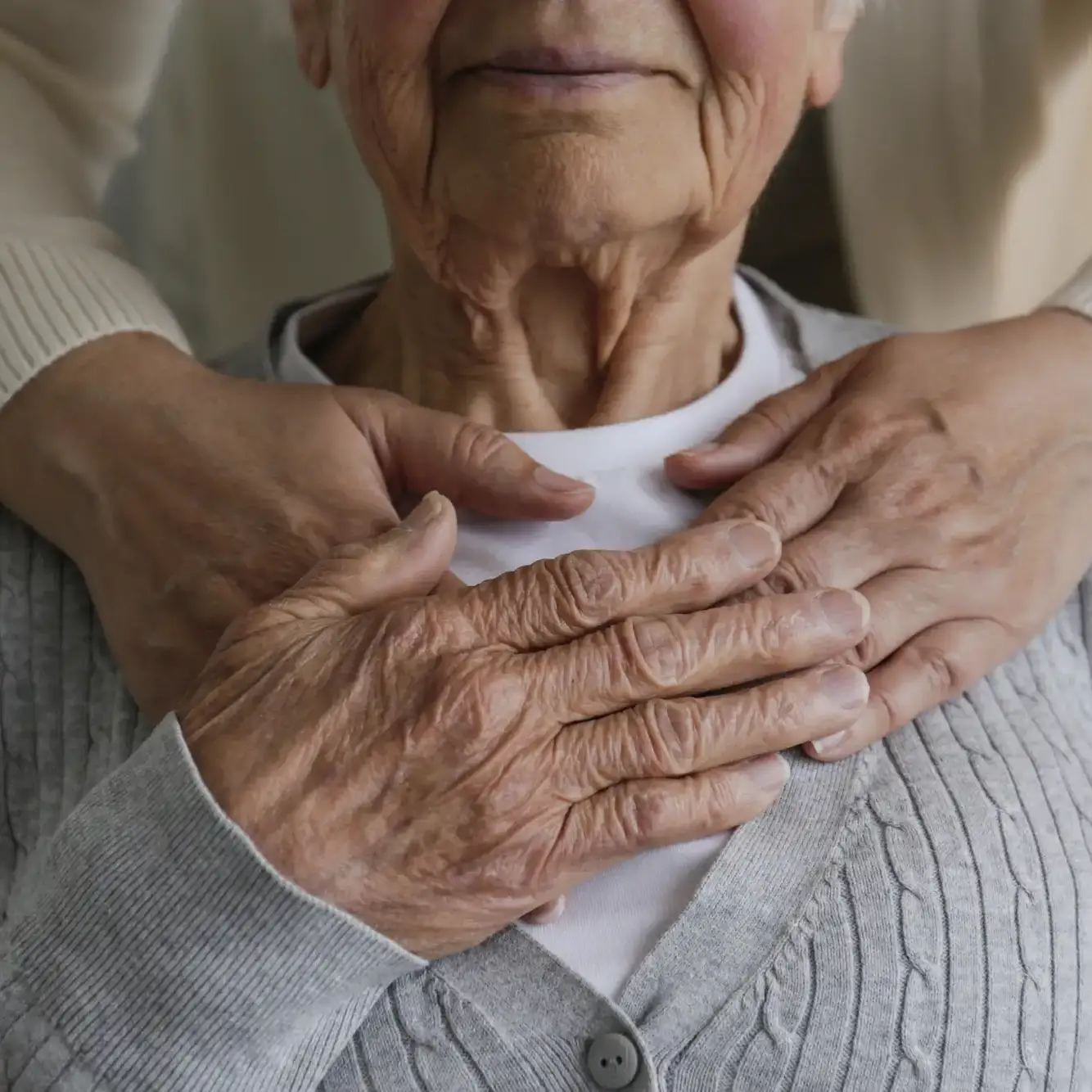 Close-up of a younger caregiver gently holding the hands of an older adult with memory loss, symbolizing compassionate Alzheimer’s & Dementia Support and Memory Care in Gainesville, FL.