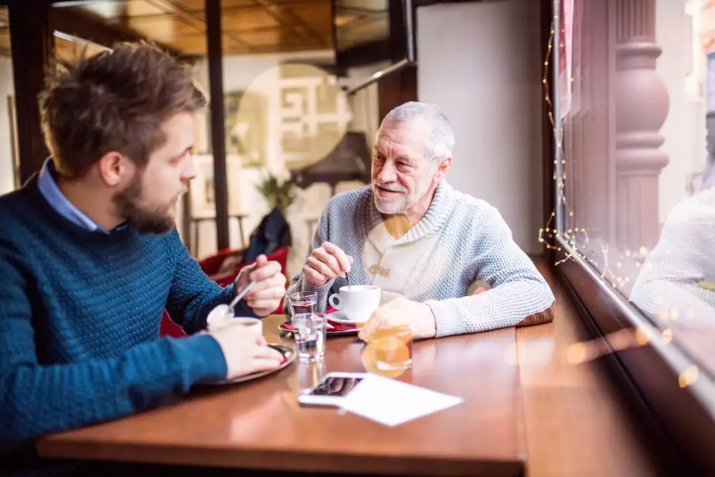 a younger man and his senior father enjoy drinks at a memory cafe