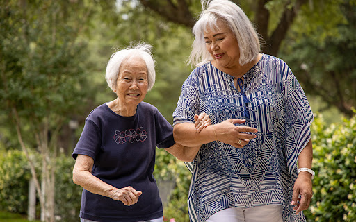 woman acting as caregiver for her mom talking a walk outside